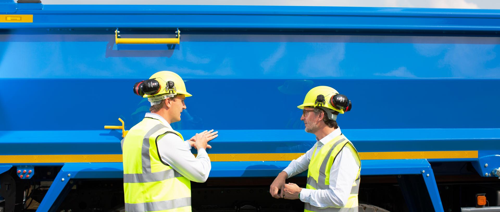 Two operatives having a conversation at the side of a blue tipper truck with a Valast surface finish