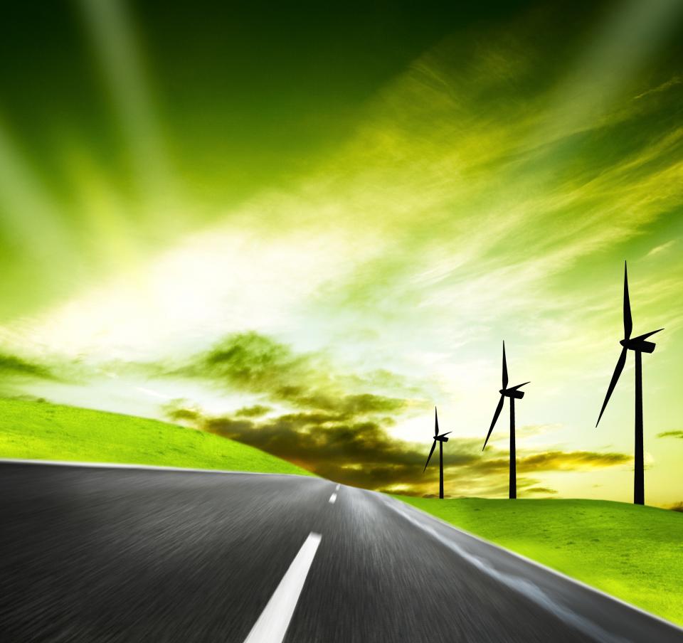 Futuristic view showing a country road with wind turbines on the right side and a green sky
